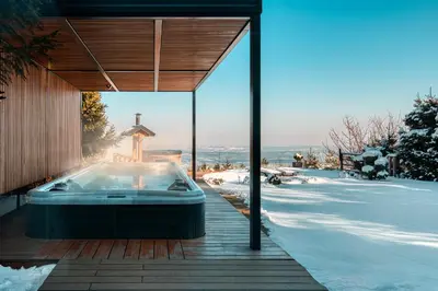 a hot tub on a deck in the snow at Panoramic View Cottage Heated Pool, Swimspa & Sauna in Pohorje