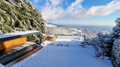 a snow covered balcony of a house with a mountain at Panoramic View Cottage Heated Pool, Swimspa & Sauna in Pohorje
