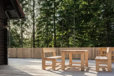 two wooden benches and a table on a patio at Cabin Storzek in Pohorje