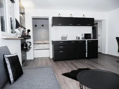 a kitchen with black cabinets and a table in a room at Victoria's Place Apartment in Ljubljana