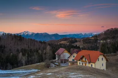a house on a hill with mountains in the background at House On The Hill (Hiška Na Griču) in Spodnja Idrija