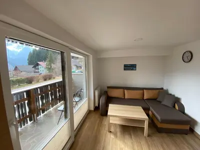 a living room with a couch and a large window at Apartma Vidovič in Rateče