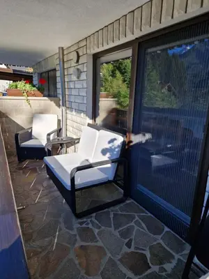 two white chairs sitting on a patio with a sliding glass door at Apartma Vidovič in Rateče