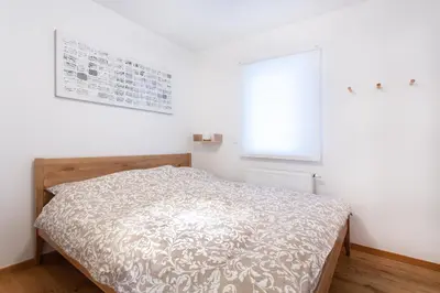 a bedroom with a bed in a white room at Alpine Home Apartment in Bohinj