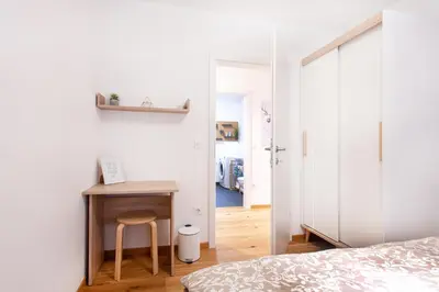 a bedroom with a bed and a table with a stool at Alpine Home Apartment in Bohinj
