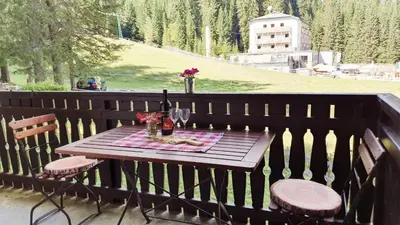 a wooden table with two chairs and wine glasses on a fence at Apartment Ski Sara Pokljuka in Bled