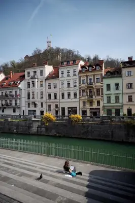 a person sitting on the ground next to a body of water at Vitez Apartment I in Ljubljana
