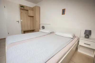 a bedroom with a bed with white sheets and a cabinet at Rooms Klik Postojna in Postojna