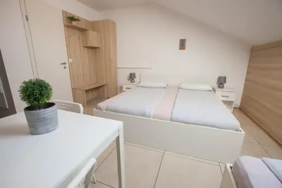 a white bedroom with a bed and a potted plant at Rooms Klik Postojna in Postojna
