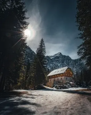 a snow covered building with a mountain in the background at Apartma BOROVC in Mojstrana