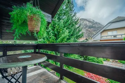 a table on a balcony with a view of a mountain at Apartma BOROVC in Mojstrana