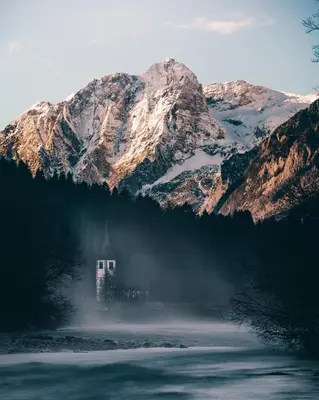 a house in front of a snow covered mountain at Apartma BOROVC in Mojstrana