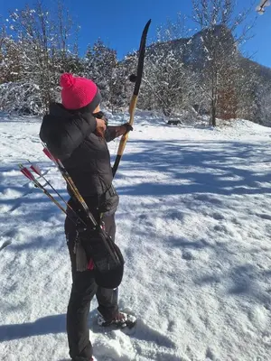 a person standing in the snow holding a stick at Rooms Ravnik in Bled