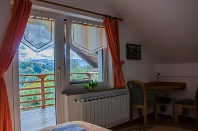 a bedroom with a window and a desk and a table at Miškar Rooms in Cerknica