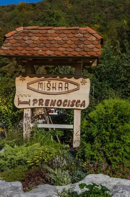 a sign in front of a house with a roof at Miškar Rooms in Cerknica