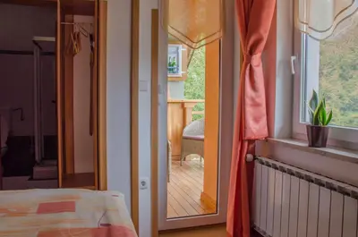 a bedroom with a door leading to a porch with a deck at Miškar Rooms in Cerknica