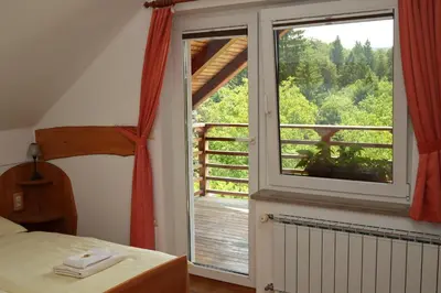 a bedroom with a large window with a view of the woods at Miškar Rooms in Cerknica