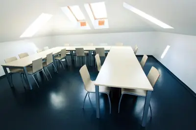 a row of tables and chairs in a room with skylights at Youth Hostel Krško in Krško