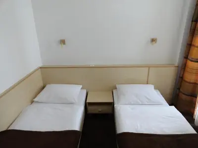two twin beds in a small room with a table at Rooms K in Maribor