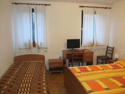 a bedroom with two beds and a desk and a television at Tourist Farm Ljubica in Poljane nad Škofjo Loko