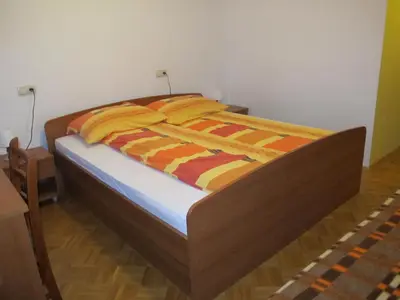 a bed with orange and yellow blankets on it at Tourist Farm Ljubica in Poljane nad Škofjo Loko