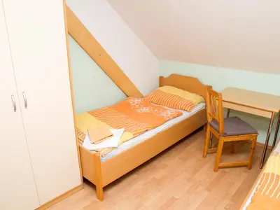a small bedroom with a bed and a desk at Guest House Pri Treh Lipah in Ptuj