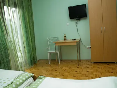 a room with a bed and a table and a television at Guest House Pri Treh Lipah in Ptuj