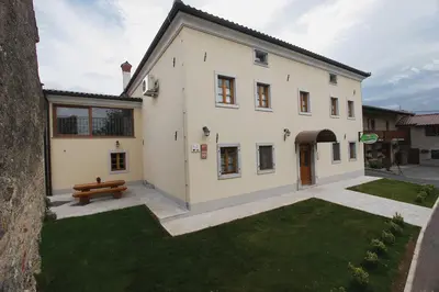 a white house with a bench in a yard at Apartments Janks in Vremski Britof