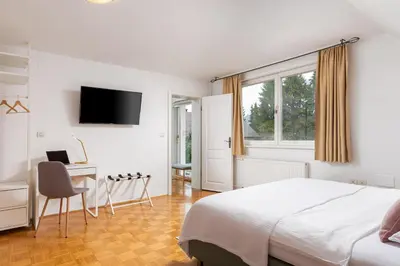 a bedroom with a bed and a desk and a television at HoMEMADE in Ljubljana