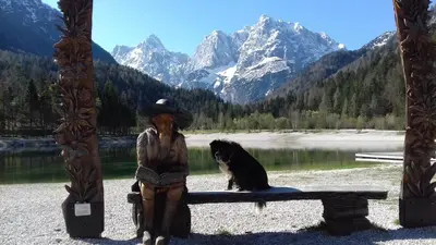 a statue of a woman sitting on a bench with a dog at Apartma Kramar Podkoren in Kranjska Gora