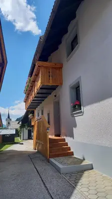 a building with a wooden staircase and a balcony at Apartma Kramar Podkoren in Kranjska Gora