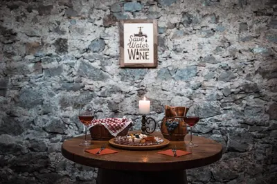 a table with a candle and two glasses of wine at Vineyard cottage Škatlar 3 in Otočec