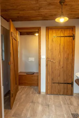 a bathroom with a wooden door and a sink at Vineyard cottage Škatlar 3 in Otočec