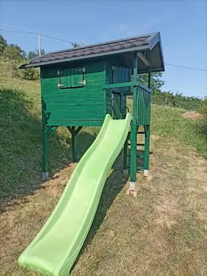 a playground with a green slide in a field at Vineyard cottage Škatlar 3 in Otočec