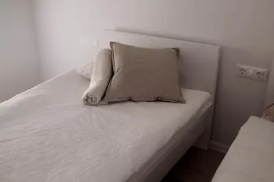 a white bed with a pillow on top of it at Deluxe Apartments Panorama in Lesce