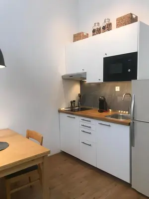 a kitchen with white cabinets and a wooden table at My Nest, 5 minutes to the Dragon Bridge in Ljubljana