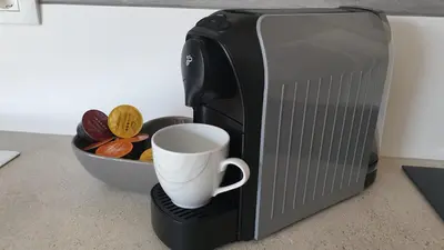 a coffee maker with a cup next to a microwave at Apartma Vovk in Mojstrana