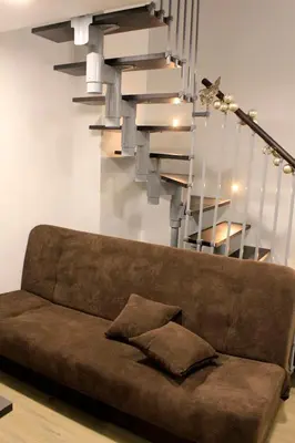 a brown couch in a living room with a staircase at Sweet getaway apartment - central & parking in Ljubljana