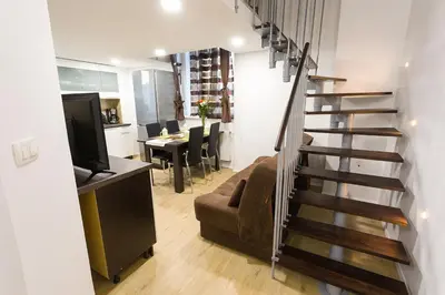 a living room with a staircase with a couch and a television at Sweet getaway apartment - central & parking in Ljubljana