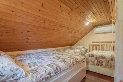 two beds in a room with a wooden ceiling at Vila Rozi, Osilnica - vacation house Pr' Vili Rozi in Osilnica