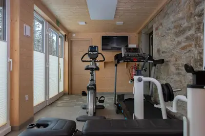 a room with a gym with a treadmill and a tv at House Storz in Pohorje