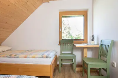 a bedroom with a bed and two chairs and a desk at House Storz in Pohorje