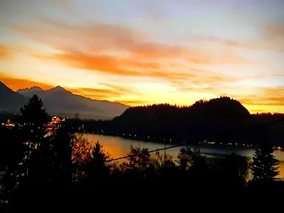 a sunset over a body of water with mountains at Apartments Barbi in Bled
