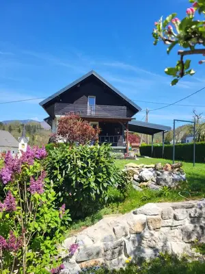 a house with a garden and some flowers at Holiday Home NA VASI in Gorenja Vas