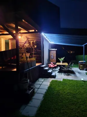 a patio lit up at night with a table and chairs at Holiday Home NA VASI in Gorenja Vas