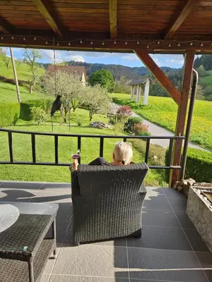a woman sitting in a chair on a porch looking at a giraffe at Holiday Home NA VASI in Gorenja Vas