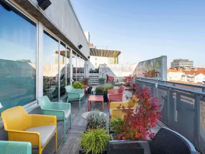 a patio with colorful chairs and tables on a balcony at ibis Styles Ljubljana The Fuzzy Log in Ljubljana