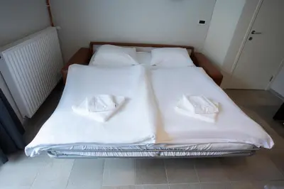 a bed with two white sheets and two pillows at Apartments Trio in Kranjska Gora