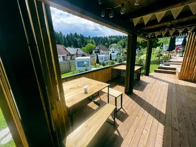 a wooden deck with a bench and a table at Glamping Langus in Topolšica