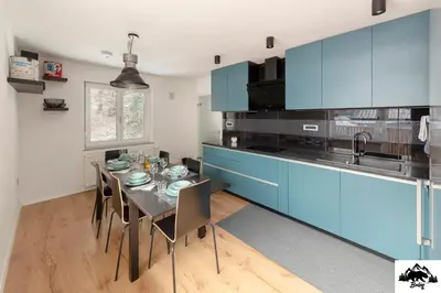 a kitchen with blue cabinets and a table with chairs at Brlog in Zgornje Gorje